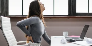 Woman at her desk suffering from back pain in Montreal