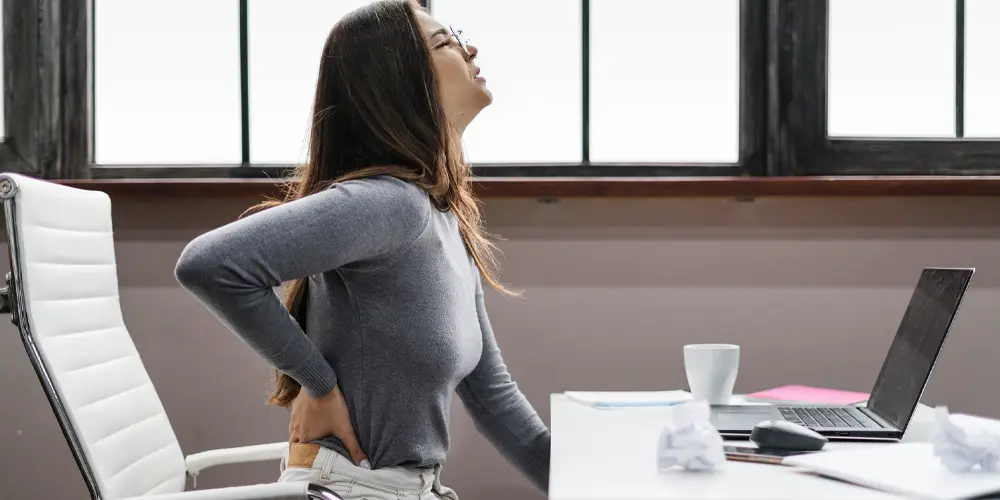 Woman at her desk suffering from back pain in Montreal